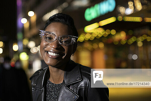 Porträt glückliche junge Frau in funky Brillen in der Stadt in der Nacht