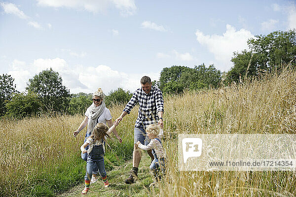 Happy family running in sunny rural field