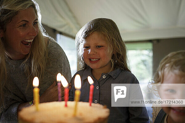 Glückliche Mutter und Tochter feiern Geburtstag mit Kuchen und Kerzen