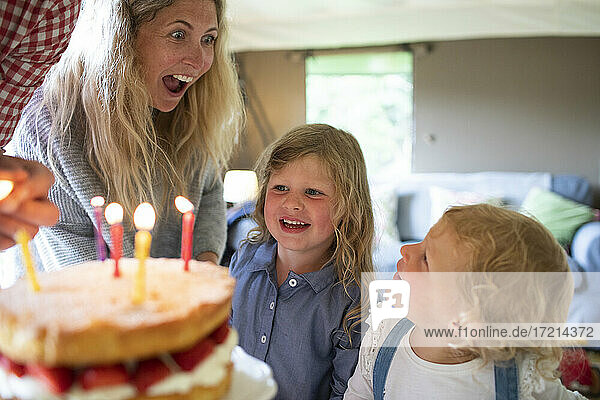 Glückliche Mutter und Töchter feiern Geburtstag mit Kuchen und Kerzen