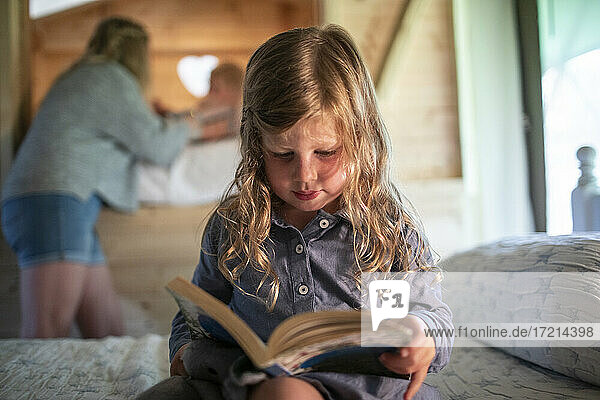 Cute girl reading book on bed