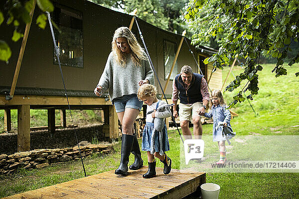 Glückliche Familie hält die Hände zu Fuß außerhalb Hütte im Wald