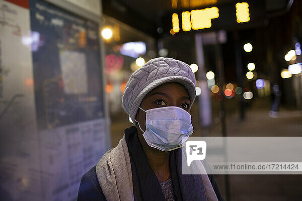 Porträt junge Frau in Gesichtsmaske auf Stadt Bürgersteig in der Nacht