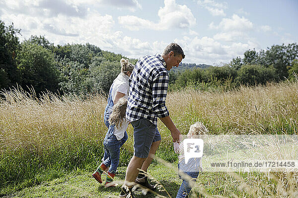 Familie hält Hände zu Fuß in sonnigen ländlichen Sommer Feld