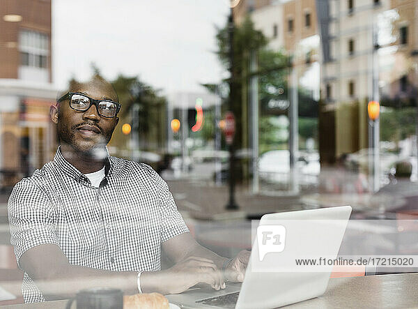 Black man using laptop in coffee shop