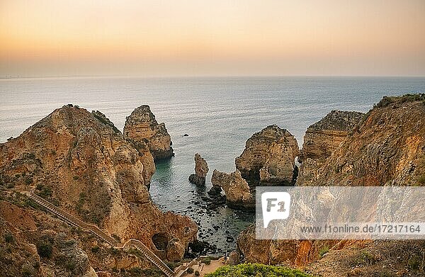 Schroffe Felsenküste mit Klippen aus Sandstein  Felsformationen im Meer  Ponta da Piedade  Morgenrot bei Sonnenaufgang  Algarve  Lagos  Portugal  Europa