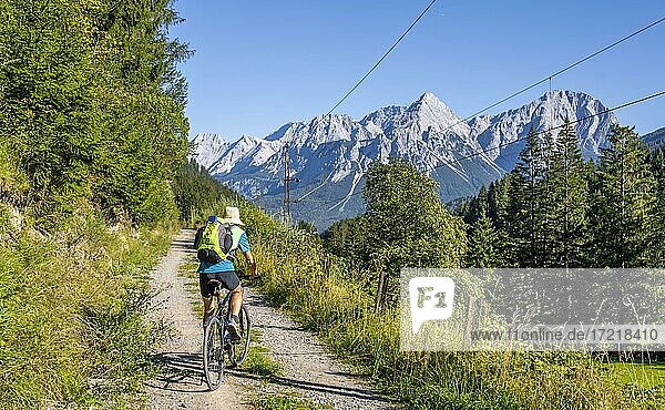 Cyclist on bike tour with mountain bike  on the bike path Via Claudia Augusta  behind Ehrwalder Sonnenspitze  Ehrwalder Becken  near Ehrwald  Tyrol  Austria  Europe