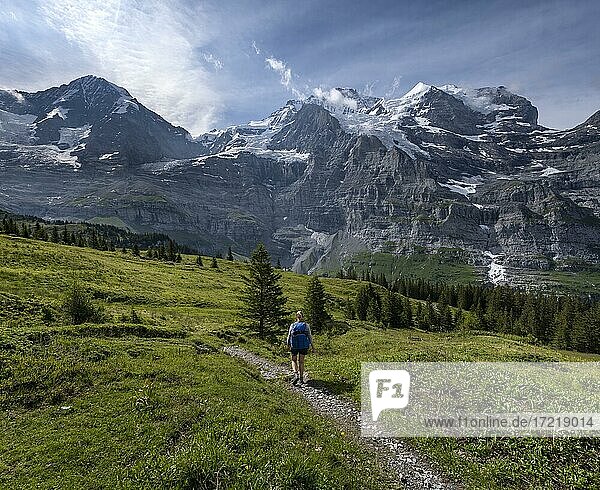 Two (hikers) on a hiking trail  in front of the Eiger north face  behind mountains and mountain tops  steep face and mountains  Jungfrau region  Lauterbrunnen  Bernese Alps  Switzerland  Europe