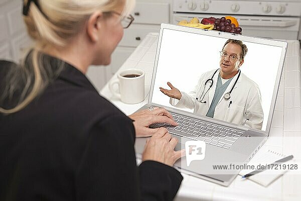 Woman in kitchen using laptop  online chat with nurse or doctor on screen
