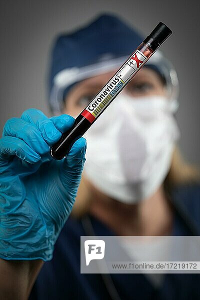 Eine Laborantin hält ein Reagenzglas mit Blut  das positiv mit dem Coronavirus COVID-19 gekennzeichnet ist