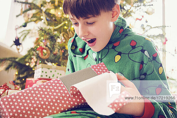 Surprised boy looking at gift box during Christmas