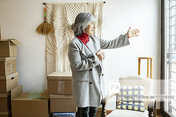 Ältere Frau mit weißen Haaren gestikuliert vor ihrem neuen Haus