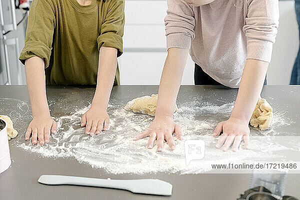 Kinder verteilen Mehl auf der Kücheninsel zu Hause