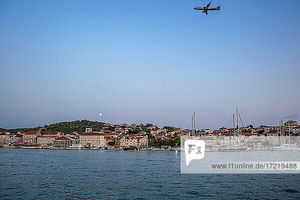 Kroatien  Gespanschaft Split-Dalmatien  Trogir  Flugzeug fliegt über die Insel Ciovo in der Abenddämmerung