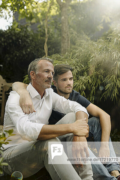 Nachdenklicher Vater und Sohn sitzen zusammen im Hinterhof
