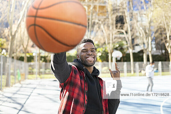 Aktiver junger Mann  der an einem sonnigen Tag Basketball spielt und gestikuliert