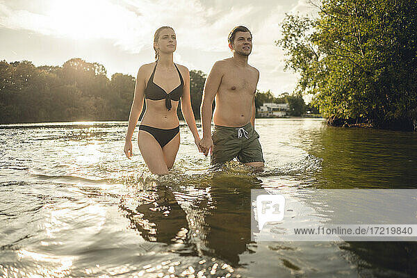 Junges Paar geht händchenhaltend aus dem See