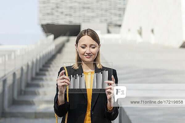 Smiling mid adult businesswoman using futuristic digital tablet outdoors
