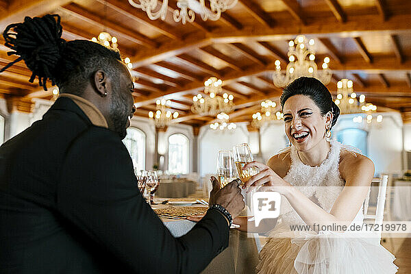 Cheerful male and female friend toasting while sitting by table at banquet
