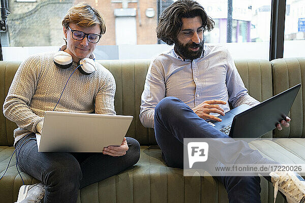 Männliche Mitarbeiter mit Laptop auf dem Sofa im Büro sitzend
