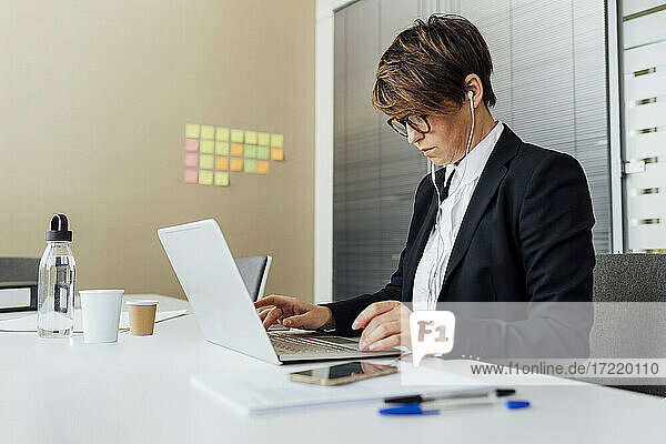 Weiblicher Geschäftsmann mit Laptop am Schreibtisch im Büro