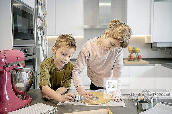 Mädchen und Junge verwenden Ausstechformen für Teig in der Küche