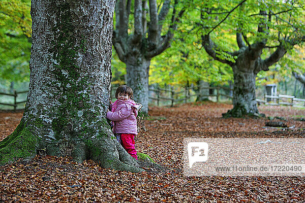 Mädchen lehnt an einem Baumstamm im Naturpark Gorbea