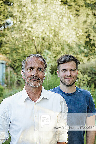 Vater und Sohn stehen an einem sonnigen Tag im Garten