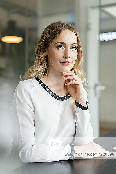 Businesswoman with hand on chin staring at desk