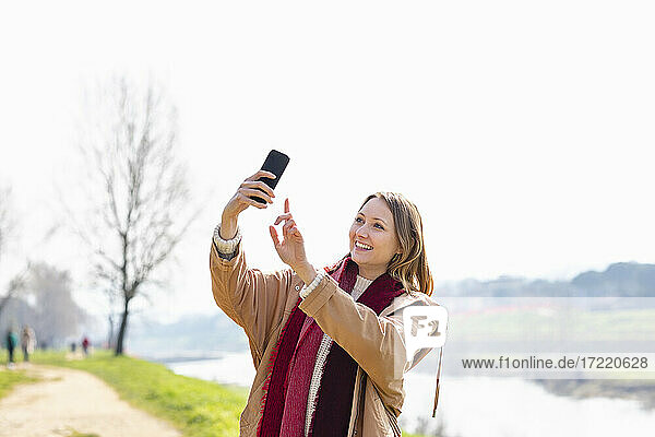 Happy woman taking selfie through mobile phone