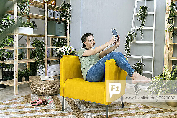 Schöne Frau nimmt Selfie durch Smartphone beim Entspannen auf der Couch zu Hause
