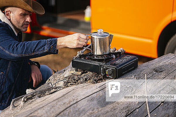 Mann kocht Kaffee auf Campingkocher