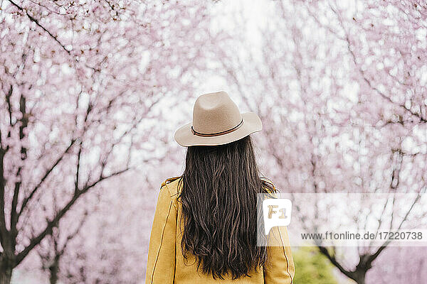 Frau mit Sonnenhut vor einem Mandelbaum im Frühling