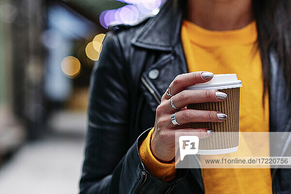 Frau mit Ringen hält Kaffeetasse in der Stadt