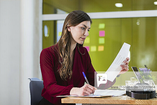 Geschäftsfrau bei der Überprüfung eines Dokuments am Arbeitsplatz