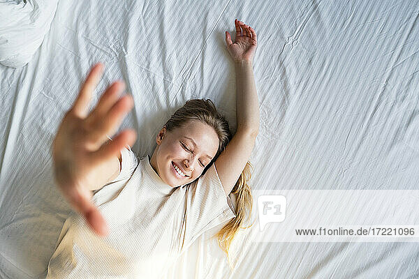 Young woman gesturing while lying on bed
