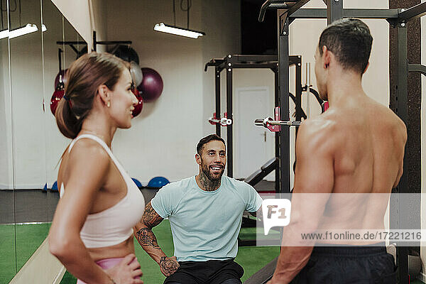 Sportler lächelt  während er seine Freunde im Fitnessstudio anschaut