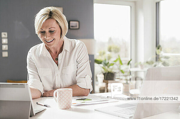 Smiling businesswoman on video call through digital tablet at home office