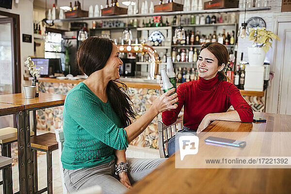 Fröhliche Freundinnen stoßen in einer Bar mit Bierflaschen an