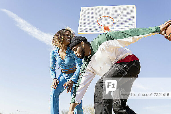Glücklicher Mann und Frau spielen Basketball auf dem Platz