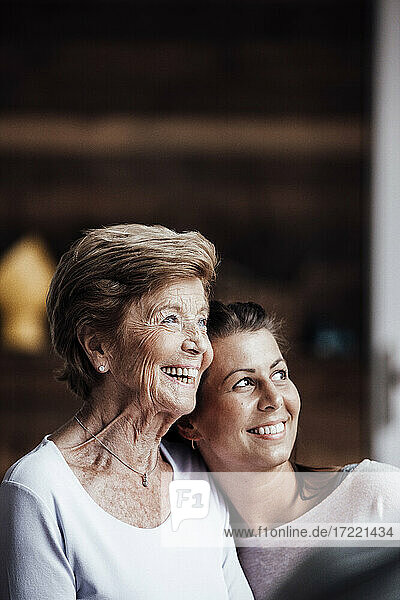 Glückliche ältere Frau und Enkelin umarmen sich  während sie wegschauen