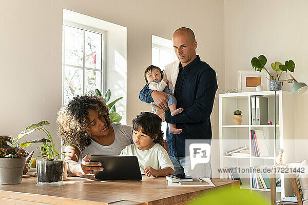Familie mit kleinem Mädchen und Tochter  die zu Hause auf ein digitales Tablet schauen
