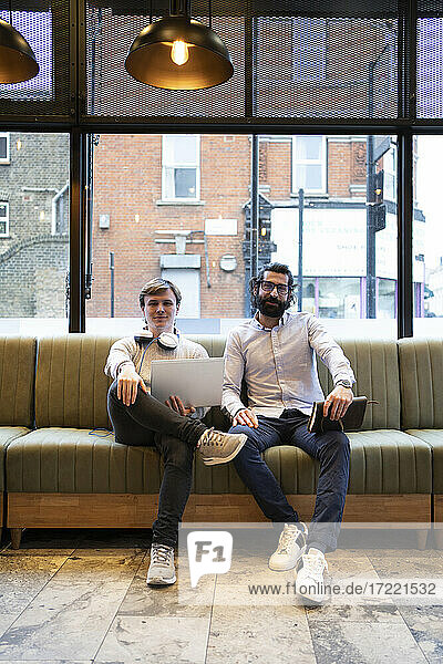 Selbstbewusste männliche Unternehmer sitzen auf dem Sofa im Büro