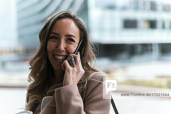Smiling blond haired businesswoman talking on mobile phone