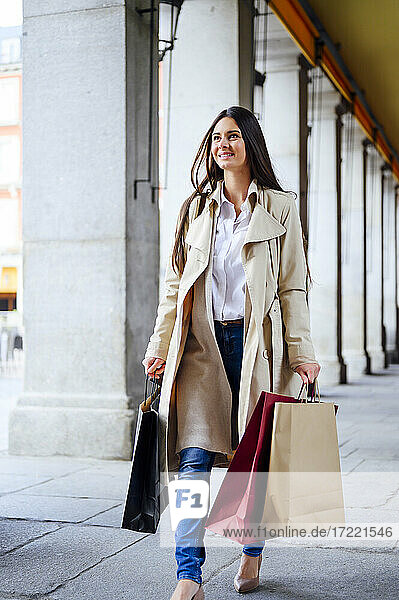 Lächelnde Frau auf dem Gehweg beim Einkaufen auf der Straße