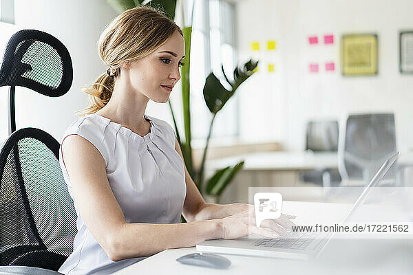 Businesswoman working on laptop at desk in office
