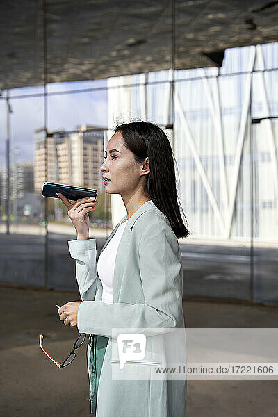 Weibliche Fachkraft telefoniert im Stehen in der Nähe eines Bürogebäudes