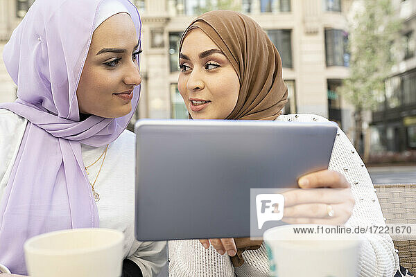 Schöne Frau mit digitalem Tablet  die eine Freundin in der Stadt ansieht