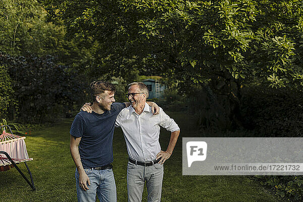 Lachender Sohn und Vater mit Arm um stehen im Hinterhof