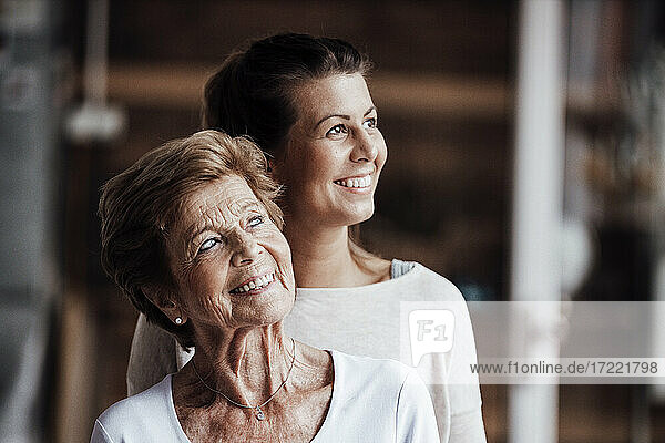 Lächelnde junge Frau und Großmutter  die zu Hause wegschauen
